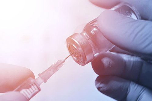 تصویر یک ویال واکسن که به وصیله سرنگ از داخل آن کشیده میشود بیرون