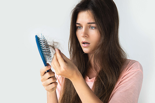 تصویری از یک زن که موهایش را شانه کرده و موهایش به شانه چسبیده، زیرا دچار ریزش مو است